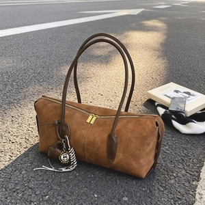 Chic brown suede boston handbag with leather handles on asphalt background street style