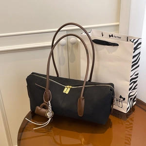 Minimalist black matte underarm bag with long brown handles and golden zippers
