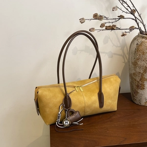 Minimalist ginger yellow leather underarm bag with double zipper on wooden surface