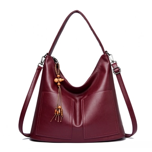 Sac à bandoulière bordeaux en similicuir avec pompons et poches avant sur blanc