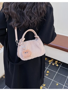 Detail der beigen Plüschtasche mit Pelz-Monster-Anhänger am schwarzen Mantel