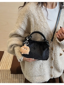 Detailaufnahme der schwarzen Plüsch-Handtasche mit Kunstfell-Textur und braunem Bommel