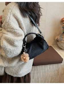 Detail der flauschigen schwarzen Handtasche mit Ledergriff und braunem Pelzanhänger