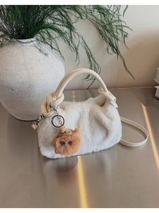 Detailansicht der cremefarbenen Plüschtasche mit Kunstfell und braunem Bärenanhänger