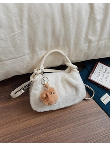 Detailansicht der weißen Plüschtasche mit dickem Griff und süßem braunem Plüschanhänger