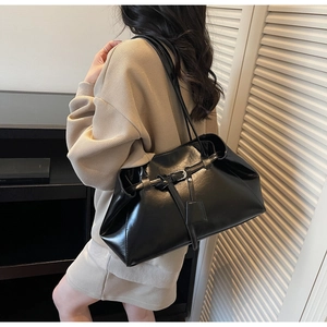 Détail du sac à bandoulière noir brillant avec boucle décorative et longue lanière