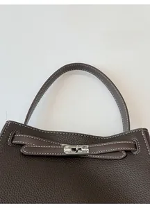 Vue détaillée de la poignée en cuir marron avec surpiqûres blanches et boucle en métal