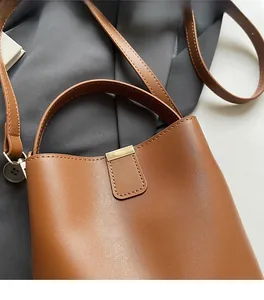 Detail of caramel bucket bag featuring lychee texture leather and gold metal clasp