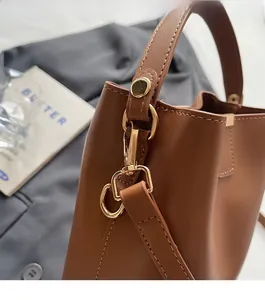Detailed close-up of brown leather bag with golden metal hardware and premium stitching