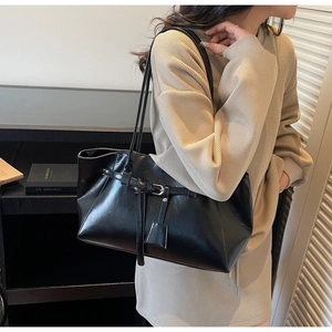 Détail d'un sac à main en cuir noir brillant avec boucle argentée et bandoulière