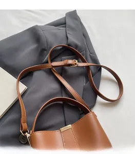 Detail view of brown bucket bag with adjustable shoulder strap and gold metal hardware