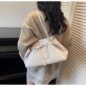 Détail du sac à épaule en cuir crème avec boucle décorative et breloque carrée