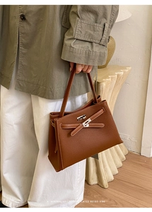 Détail d'un sac à main en cuir marron avec boucle rotative argentée et texture grainée