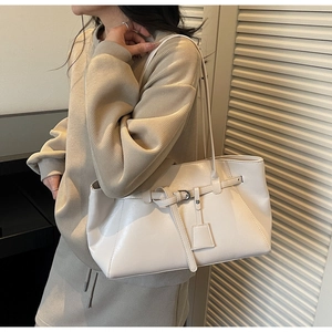 Détail d'un sac cabas en cuir blanc cassé porté avec un pull en maille douce pour le style