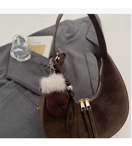 Dettaglio borsa hobo in pelle scamosciata marrone con cinturino e ciondolo guanto
