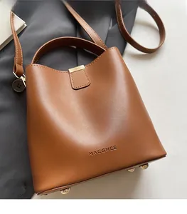 Detail of brown leather bucket bag featuring gold metal buckle and embossed brand logo
