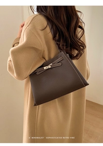 Sac fourre-tout en cuir marron avec fermoir en métal porté par un mannequin en manteau