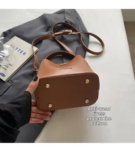 Detail view of the caramel leather bucket bag featuring gold bottom protective rivets