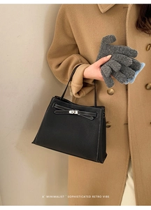 Détail d'un sac à main en cuir grainé noir avec coutures blanches et fermoir argenté