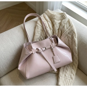 Détail d'un sac cabas en similicuir rose pâle avec boucle sur un canapé beige