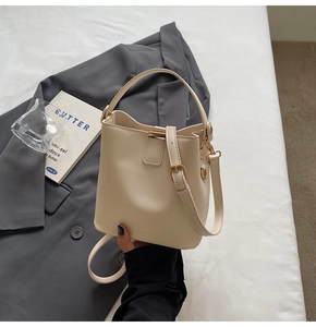 Detail view of cream bucket bag showing smooth leather texture and adjustable strap