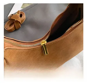 Dettaglio della cerniera dorata e della pelle opaca marrone della borsa a tracolla