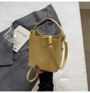 Detail of lemon yellow leather bucket bag with top handle and gold magnetic closure