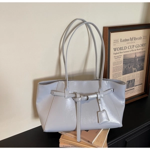 Détail d'un sac cabas en cuir bleu glacier avec boucle sur des livres vintage