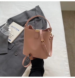 Pink leather bucket bag close-up with gold hardware and MACGHEE logo on a clean desk