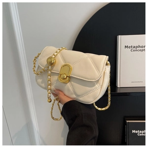Detail of cream quilted crossbody bag with gold chain strap and decorative metal ball