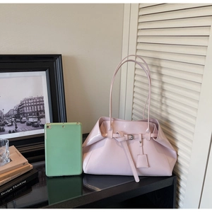Détail du sac à main rose clair en cuir brillant avec plis latéraux et boucle en métal décorative