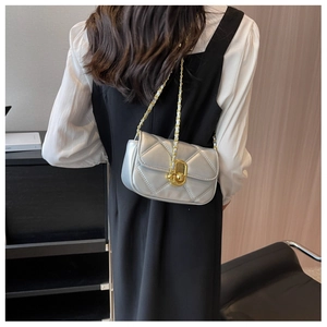 Detail of silver quilted chain bag featuring gold twist lock and metallic finish on shoulder