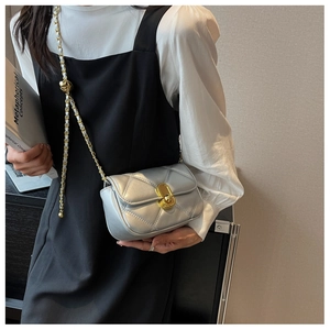 Detail of silver quilted crossbody bag with gold twist lock and metal chain strap