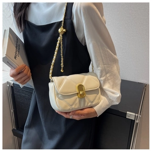 Detail of white quilted crossbody bag featuring a gold chain strap and turn-lock closure