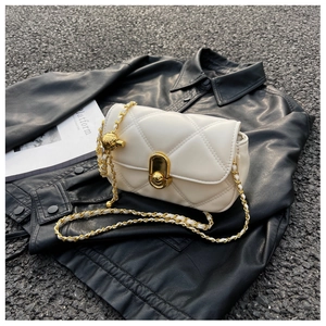Detailed macro shot of beige quilted cross-body bag featuring a gold chain and metal ball