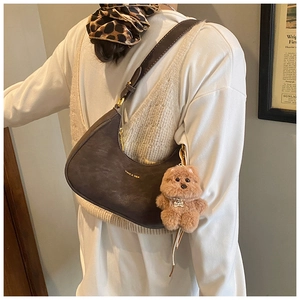 Dettaglio borsa hobo in pelle opaca marrone con ciondolo a orsetto e finiture dorate