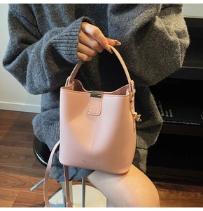 Close-up of pink bucket bag featuring fine leather texture and metal lock detail