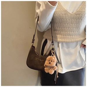 Dettaglio borsa a mezzaluna marrone scuro con texture vintage e ciondolo cane peluche