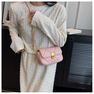 Detail of pink quilted texture and golden sphere buckle on crossbody chain bag