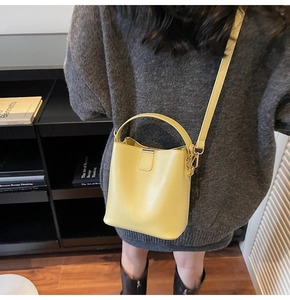 Detailed back view of a lemon yellow leather bucket bag worn with a crossbody strap