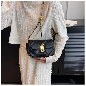 Detail of black quilted crossbody bag with gold chain strap and metal ball adjuster