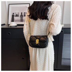 Classic black quilted leather crossbody bag with gold hardware worn by a model
