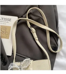 Detailed texture of off-white lychee leather bucket bag with pearl lace bow charm