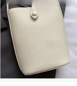 Detailed macro view of the creamy white lychee pattern leather texture on a bucket bag