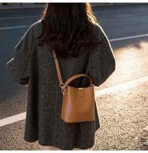 Caramel bucket bag worn by model in a stylish grey wool coat on an urban street