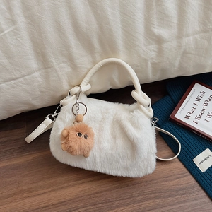 Schicke weiße Kunstpelz Handtasche mit Plüschbommel und Umhängeriemen in gemütlicher Deko
