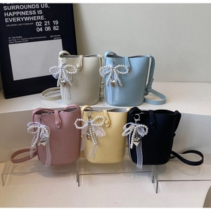 Macro shot of colorful mini bucket bags with pearl bow charms and lychee texture