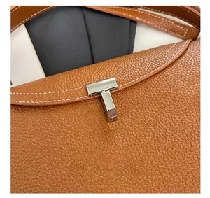 Gros plan d'un sac en cuir marron avec fermoir en T argenté et surpiqûres blanches