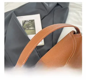Détail d'un sac cabas en cuir marron avec coutures blanches et boucle en métal argenté