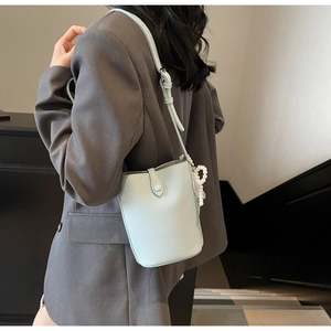 Detail of light blue lychee leather bucket bag featuring a decorative pearl charm